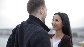 A photo of a foreign man and Asian woman happily looking into each other’s eyes